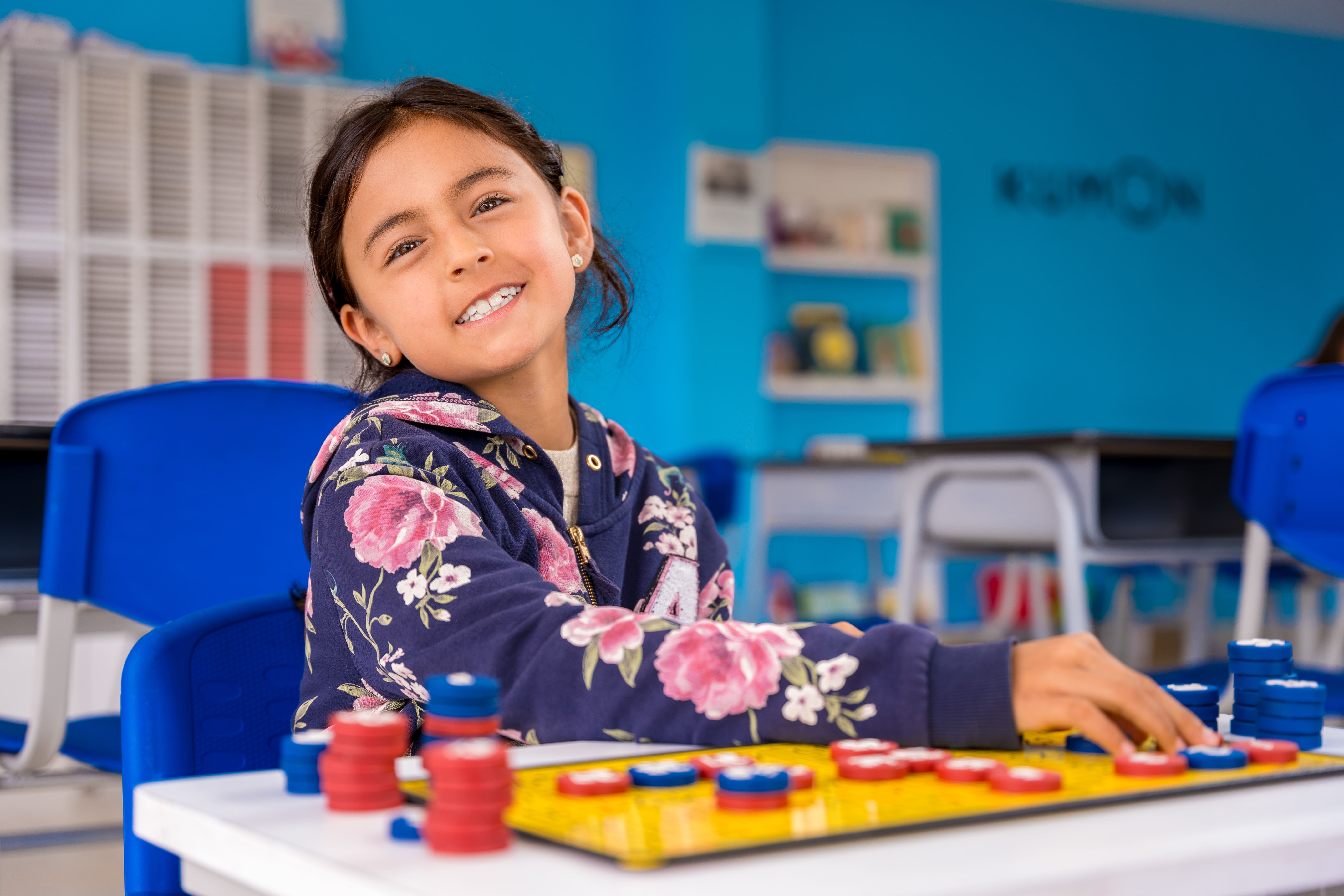 Niña estudiando matemáticas básicas con tablero magnético en un centro Kumon, disfrutando del aprendizaje-Chile