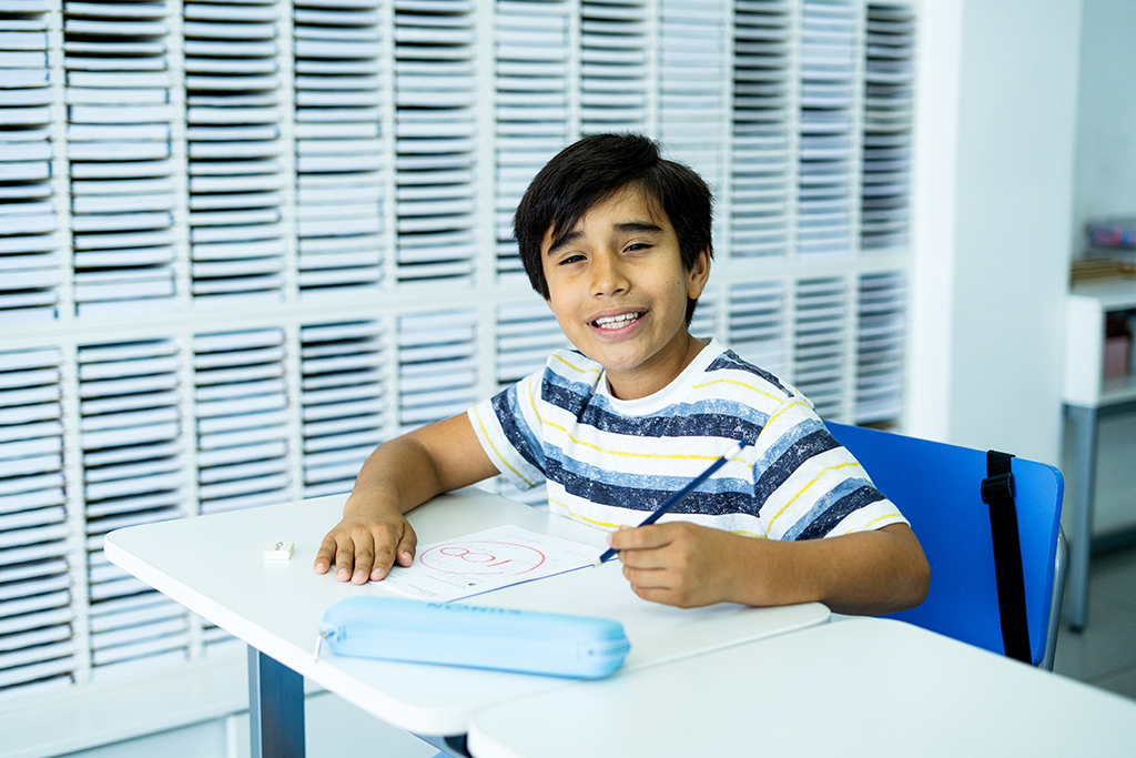 Alumno sentado, sosteniendo un lápiz y sonriendo en el aula de un centro Kumon-Chile