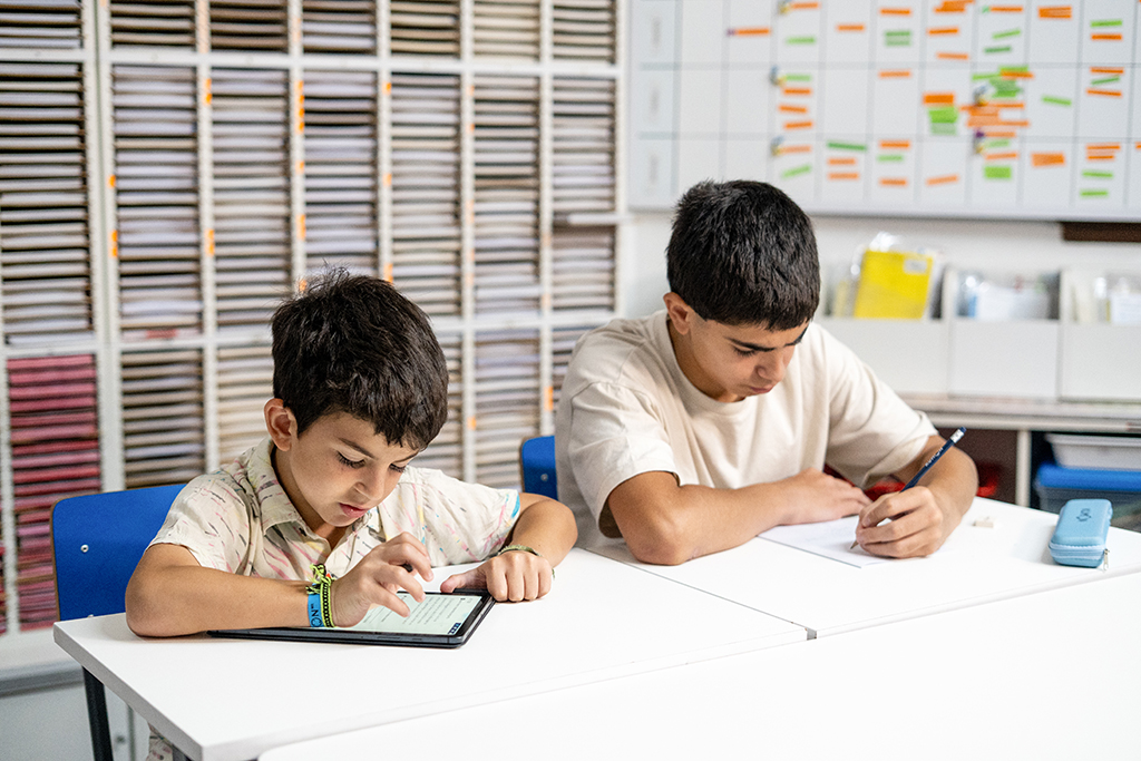 Dos estudiantes en un aula de Kumon, uno trabajando en una tableta y otro escribiendo en papel-Chile