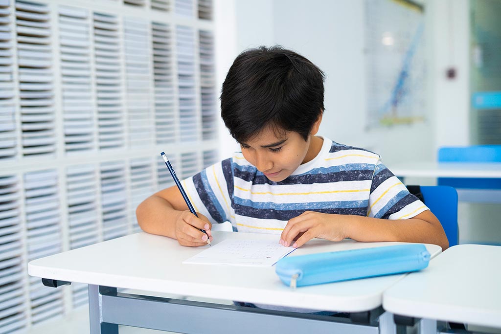Niño concentrado resolviendo ejercicios en papel como parte del método de estudio individualizado de Kumon-Chile
