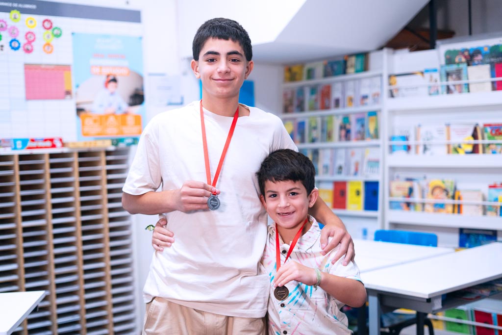 Dos estudiantes en un centro Kumon mostrando orgullosamente sus medallas por logros educativos-Chile