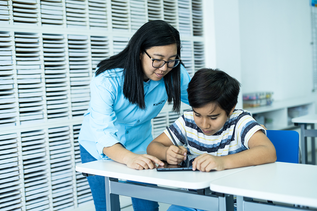 Orientador guiando a un estudiante mientras utiliza una tableta para el aprendizaje individualizado en el aula-Chile